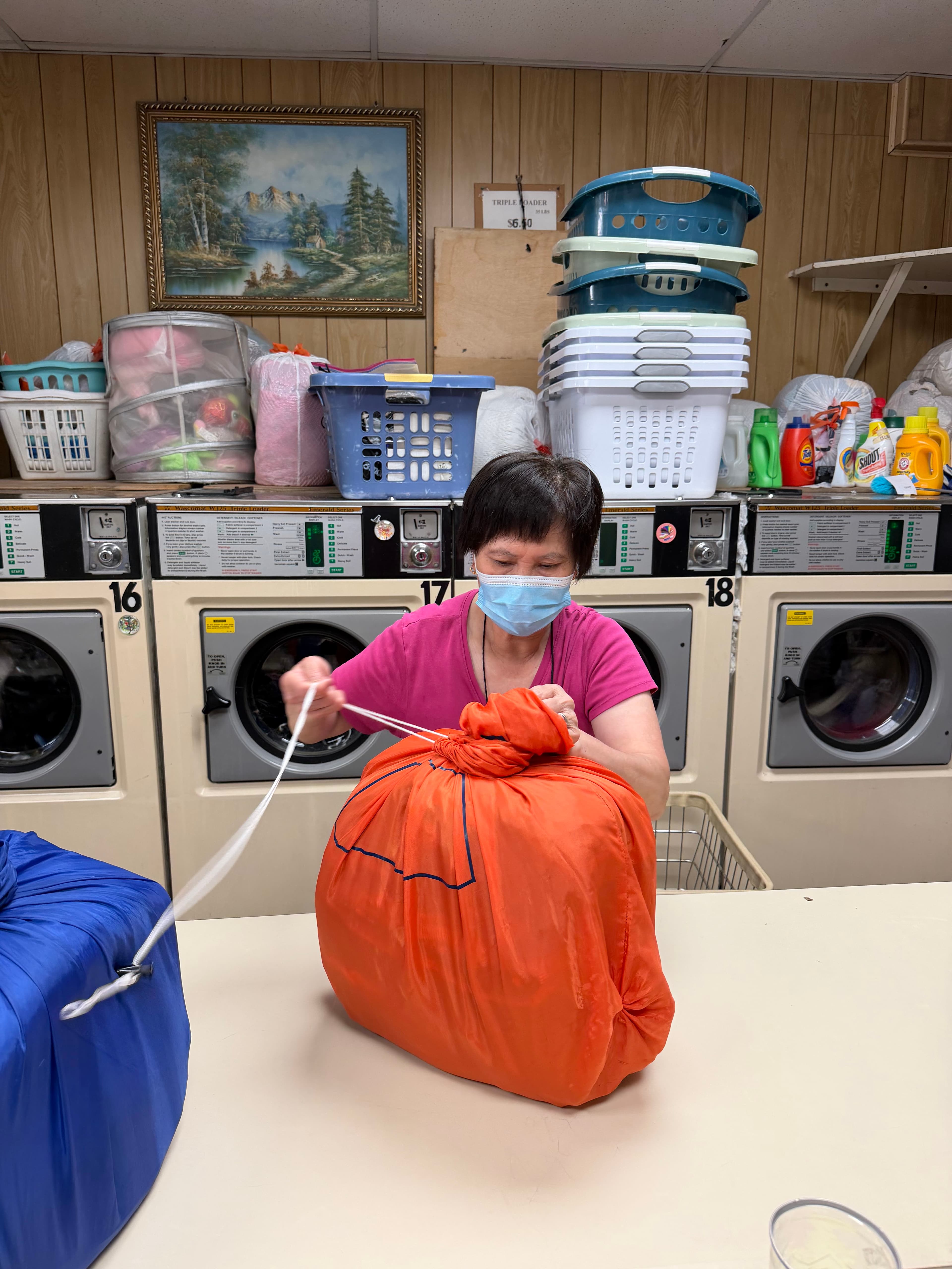 A Mars Laundromat employee tying closed a finished laundry bag between rows of washers and dryers